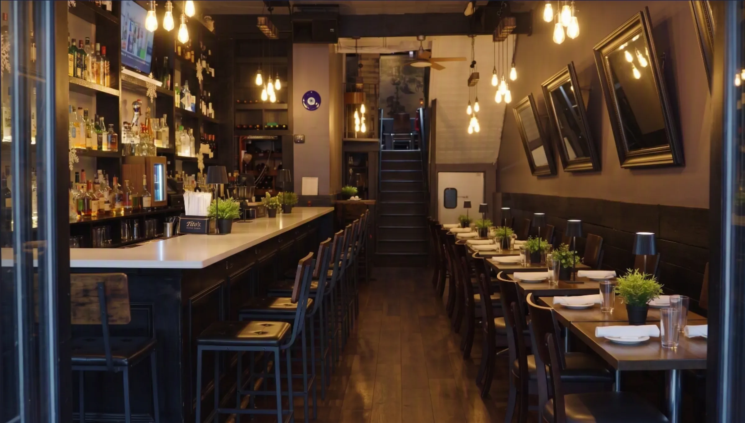 Wide view of Mezè DC's main floor, set tables beside the bar under glowing pendant lights